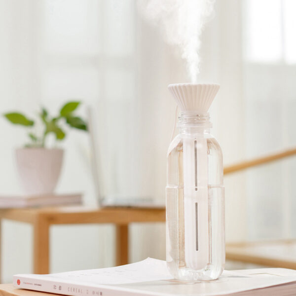 Portable humidifier for plants in use indoors, next to a healthy potted plant, maintaining humidity.