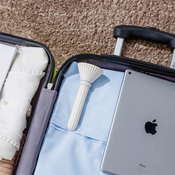 Portable humidifier for plants in a suitcase with a laptop, emphasizing its portability and safety for travel.